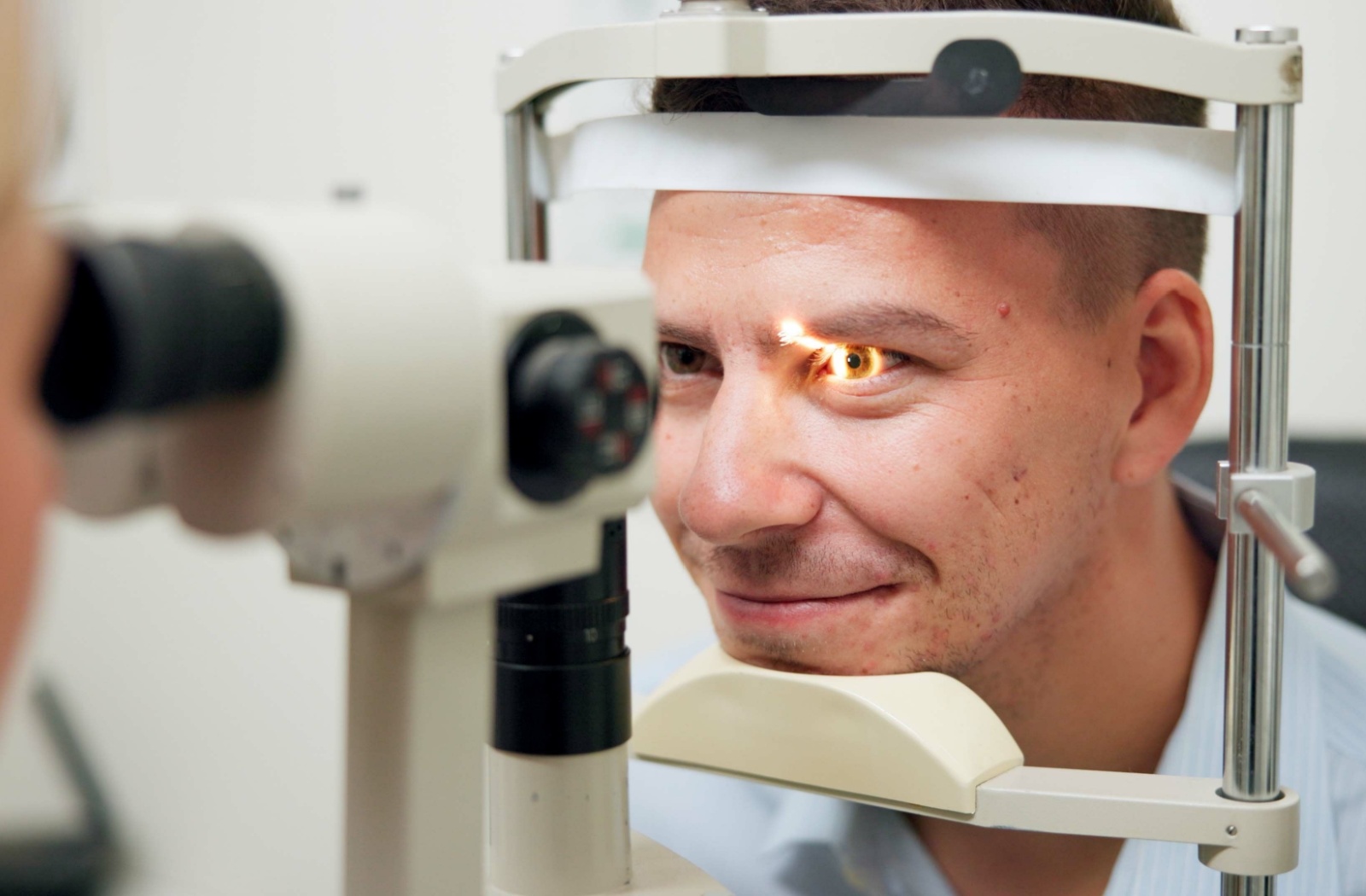 A patient has their eye examined by an optometrist using a slit lamp.