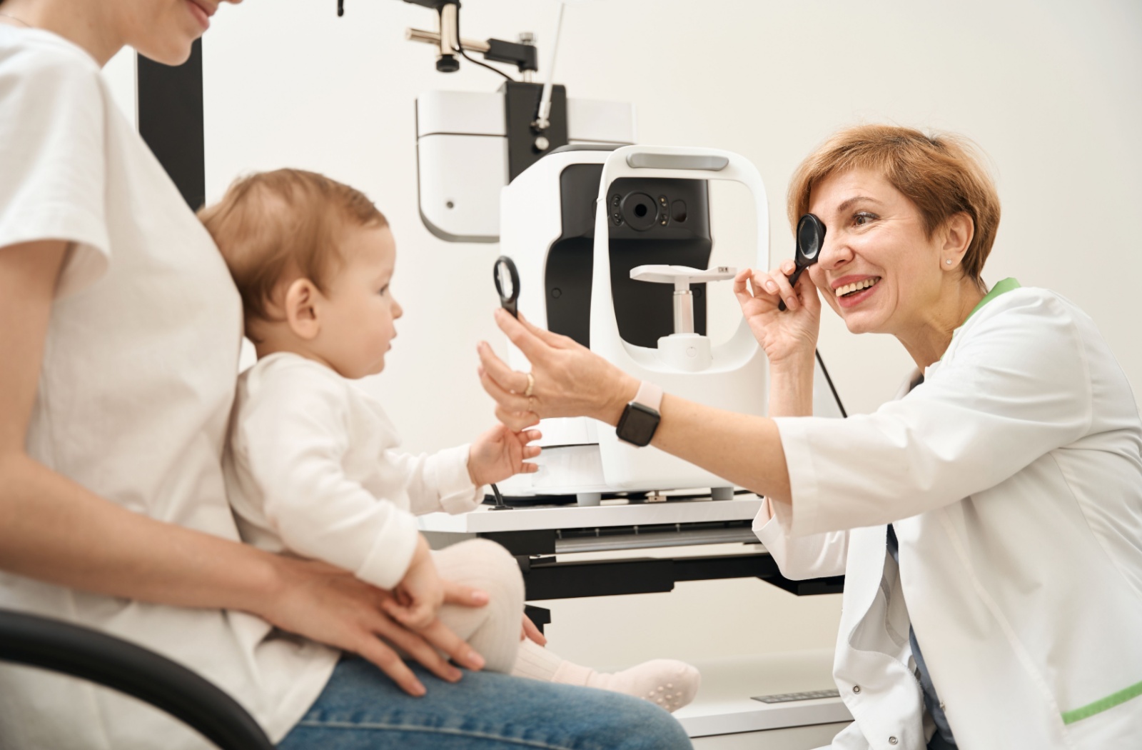 Toddler is examined by smiling optometrist during eye exam.